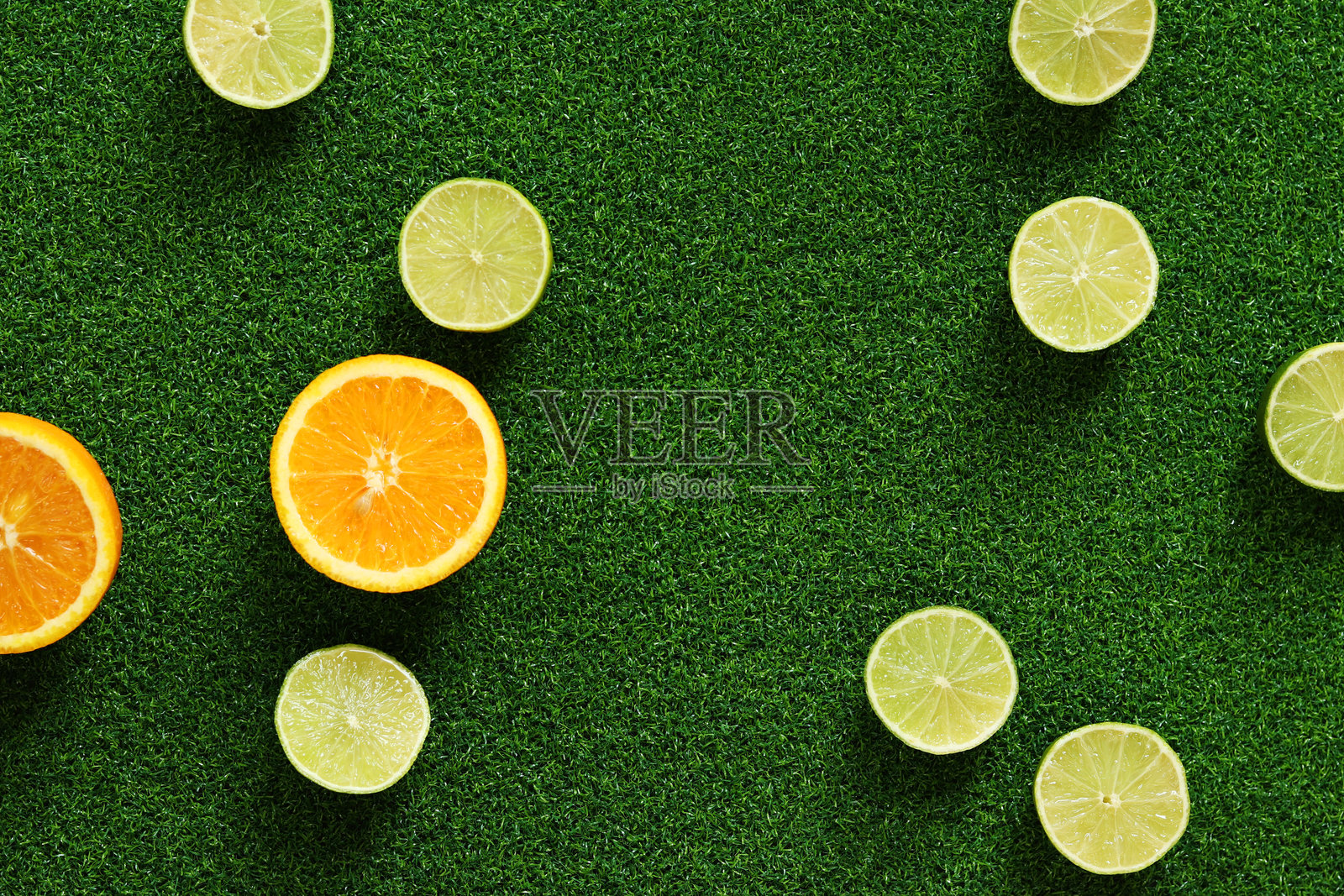 草地背景上的橙子和青柠切半，俯视图照片摄影图片