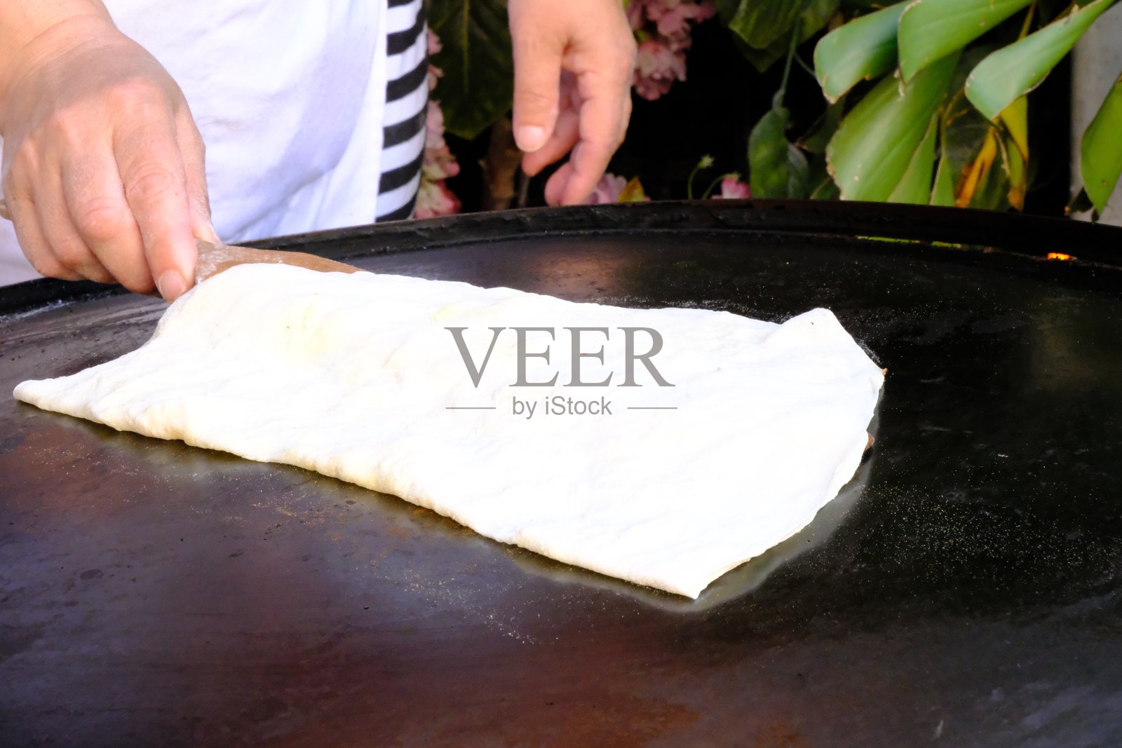 一位家庭主妇正在用擀面杖擀制传统土耳其美食 gözleme（一种扁面包），然后在烤盘上烹饪，最后呈现出来。照片摄影图片