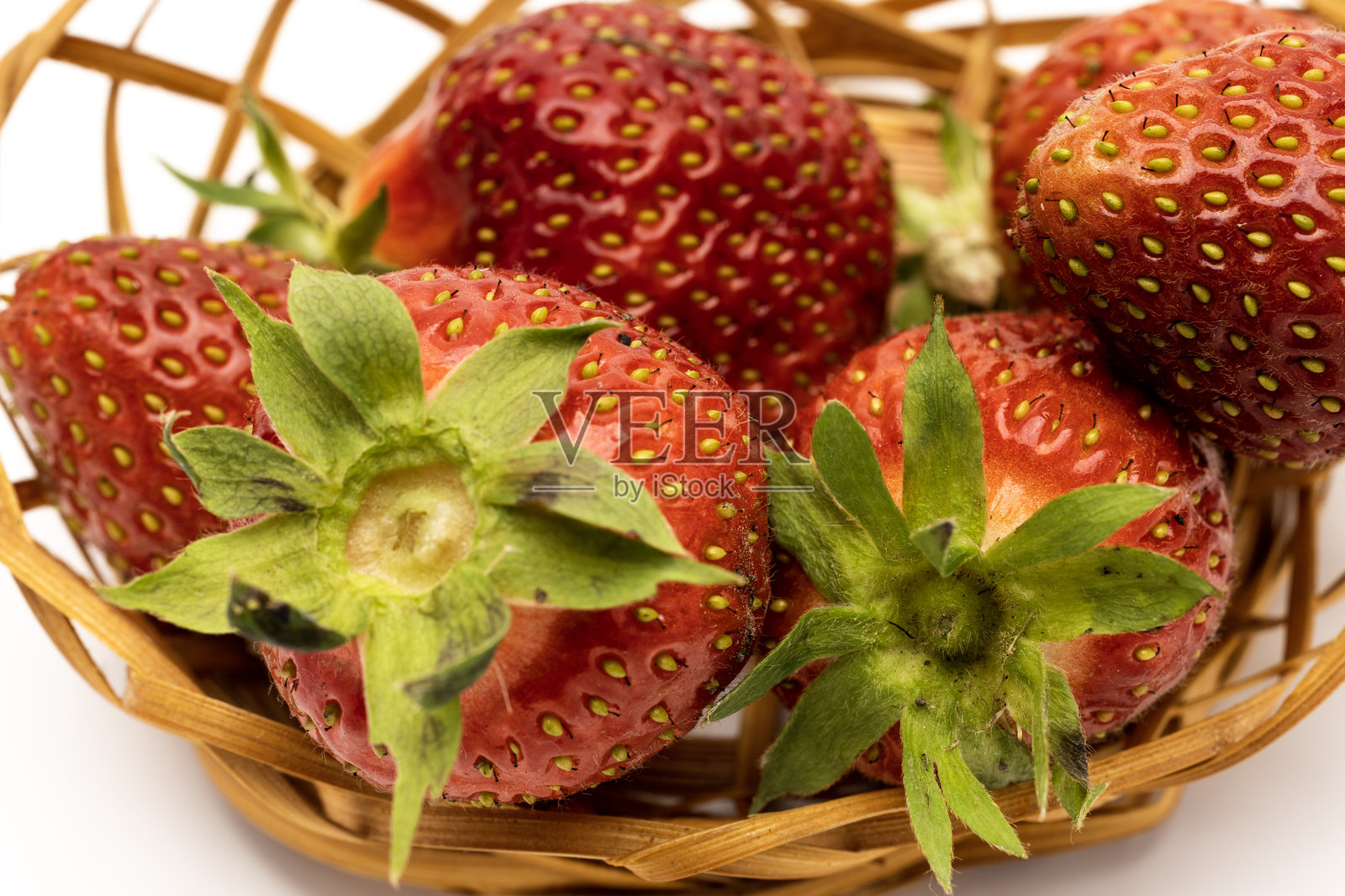 新鲜成熟的草莓特写，放在编织的篮子里。草莓鲜红欲滴，搭配绿色叶子，展现出多汁的质感。照片摄影图片