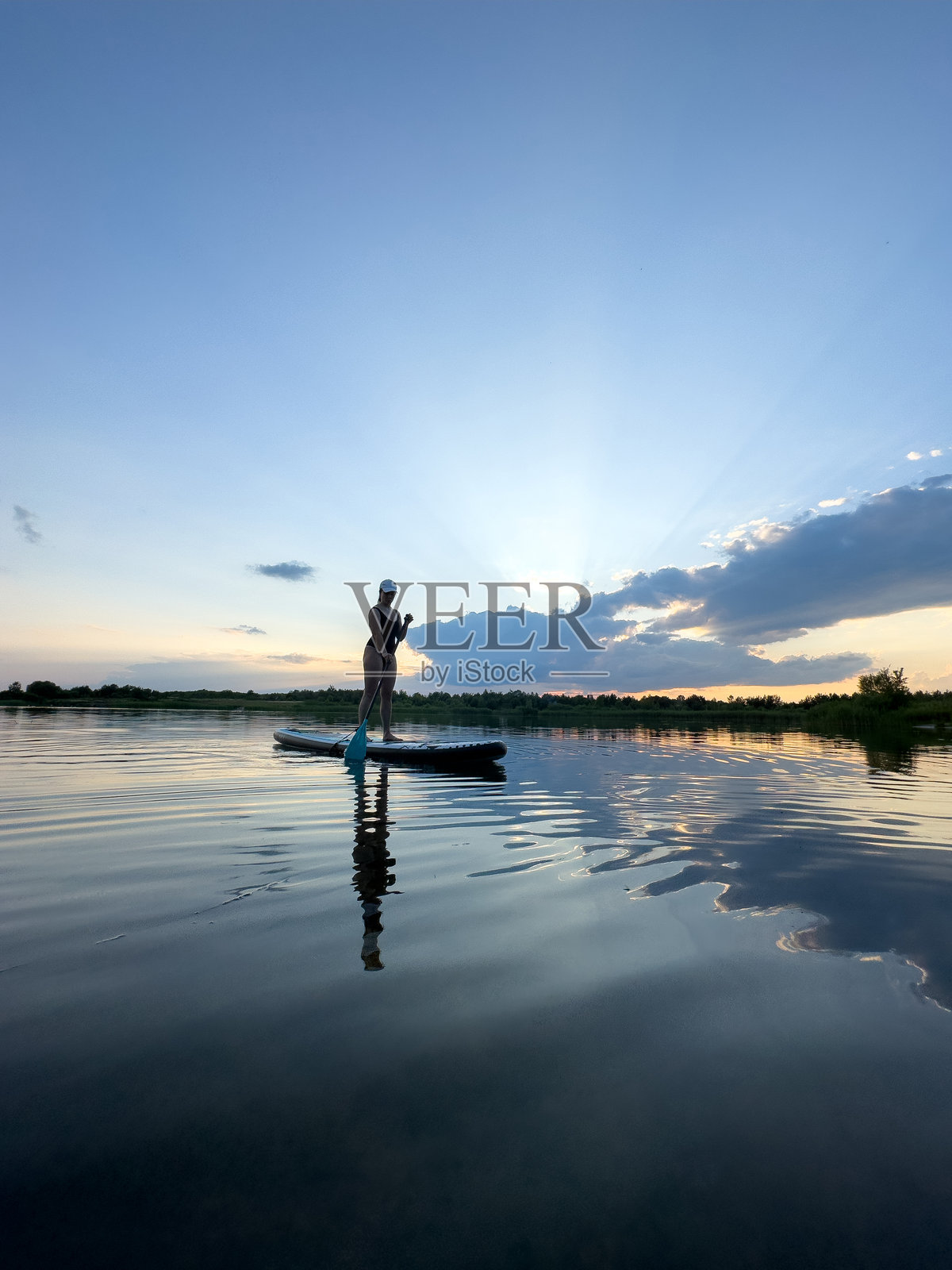 在宁静湖泊上日落时的立式划水照片摄影图片