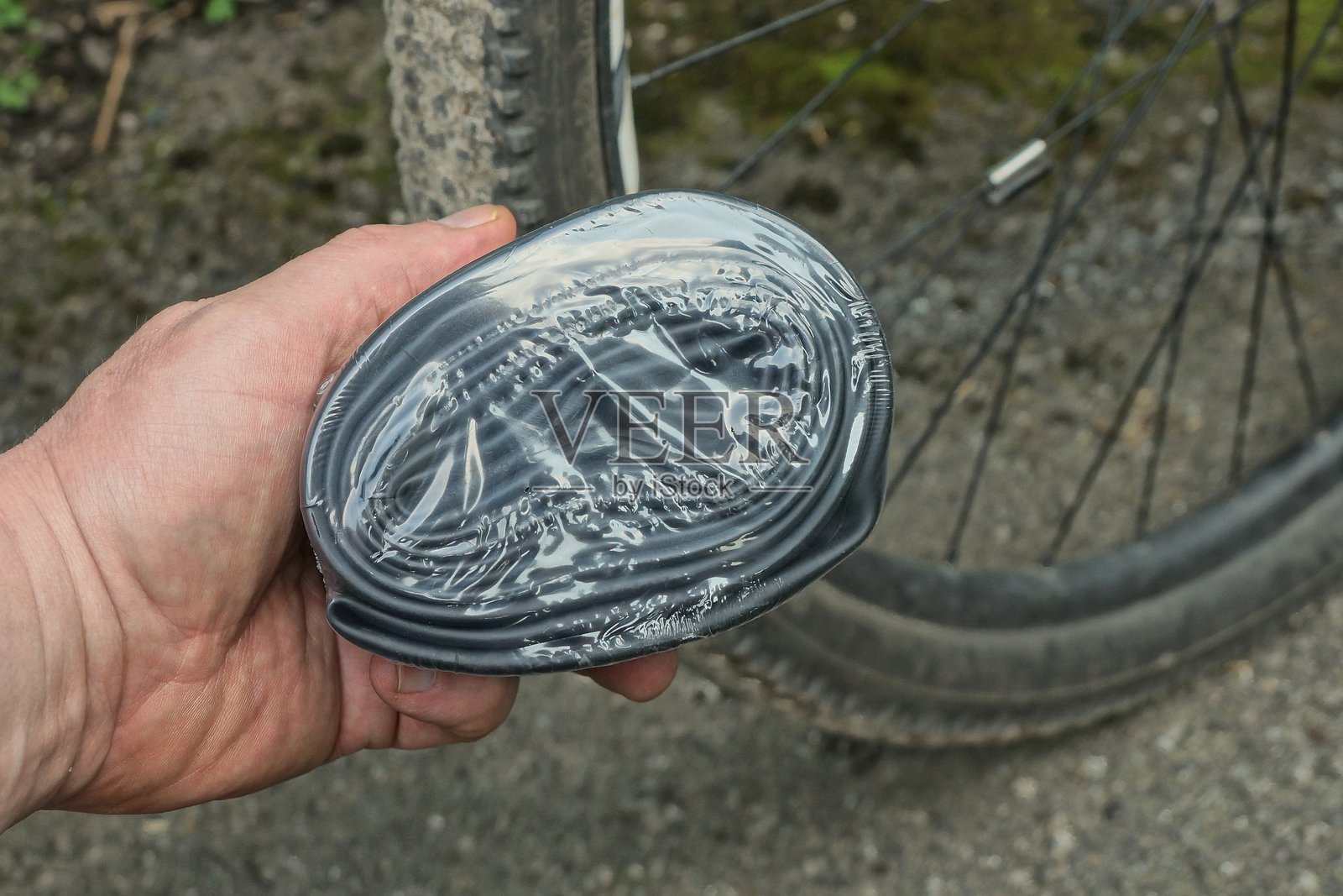 手握一根装在包装里的黑色橡胶自行车内胎照片摄影图片