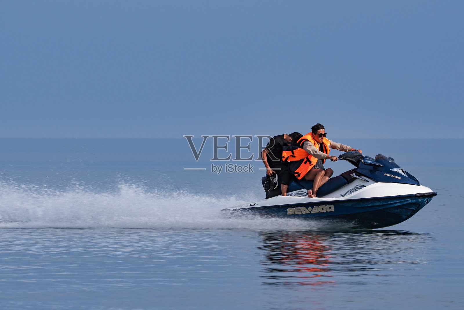 两名亚洲男子在伊塞克湖上驾驶个人水上摩托。照片摄影图片