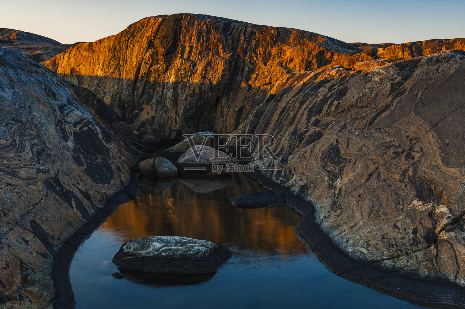 金色的光芒为瑞典海岸的岩石形成投射出温暖的光辉。照片摄影图片