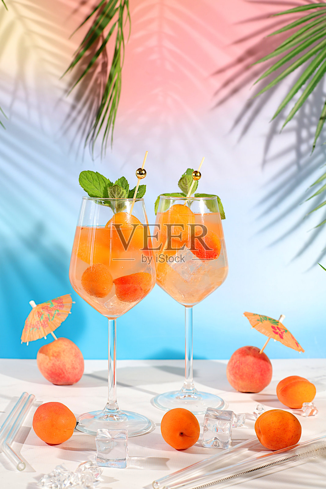 现代静物水果摆设。皇家柠檬水鸡尾酒配桃子、杏子，莫吉托鸡尾酒配龙舌兰、金酒、朗姆酒、冰块和新鲜薄荷，酒吧和派对概念，餐厅和咖啡馆广告卡。照片摄影图片