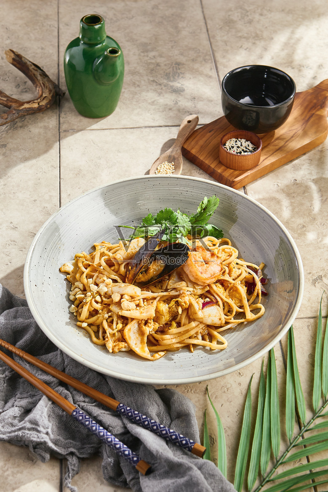 在明亮的自然光下，海鲜炒面，俯视构图，搭配乡村风格的陶瓷盘。照片摄影图片