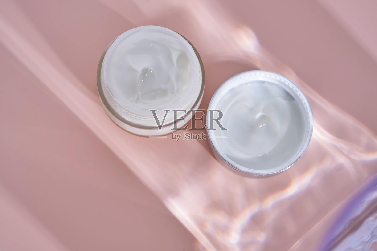 一个打开的奶油罐，罐内的质地在粉色背景上。照片摄影图片