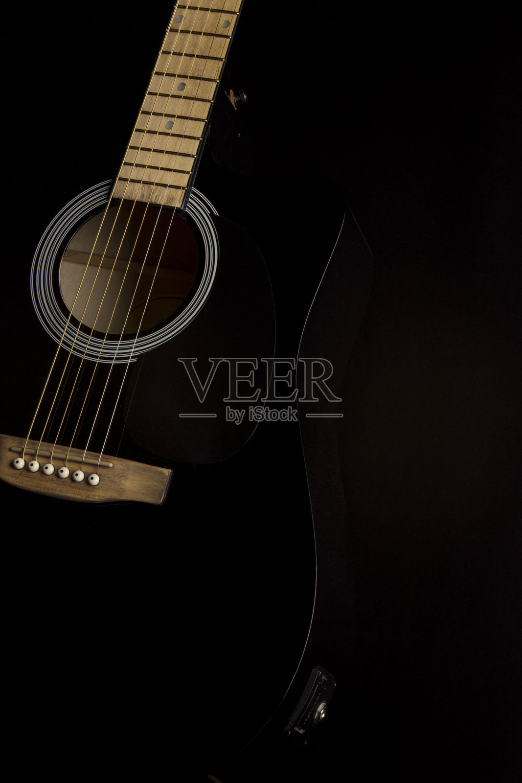 black guitar on a dark background. a shadow. the background. close-up. side view.照片摄影图片