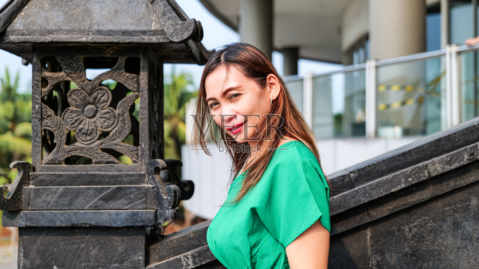 一位穿着绿色裙子的美丽女性正在户外的楼梯上走。照片摄影图片