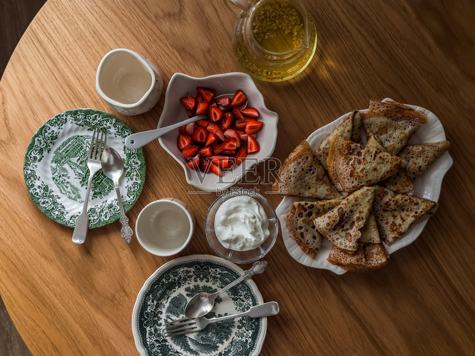 美味的早餐，早午餐 - 薄饼、奶油、新鲜草莓，圆形木桌上的绿茶照片摄影图片