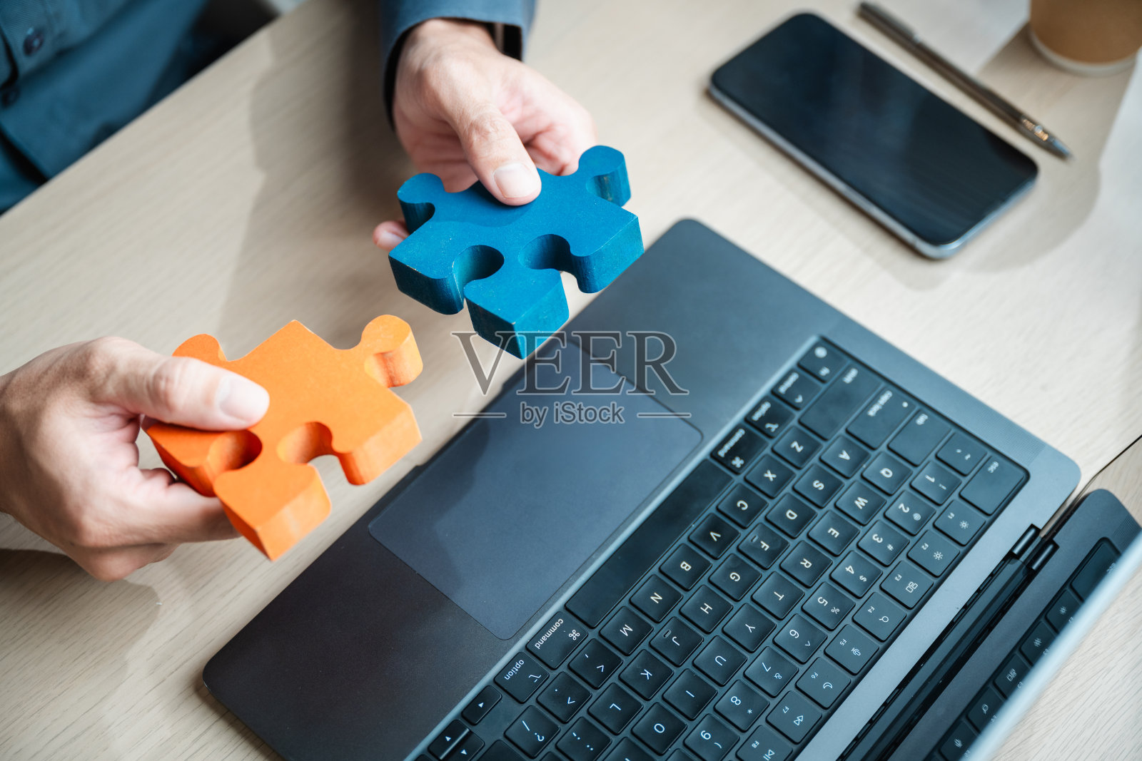 拼图，商业解决方案。合作团队战略。拼图成功。一名男子手中握着两块拼图，将它们放在笔记本电脑上。合作与团队工作的概念。照片摄影图片