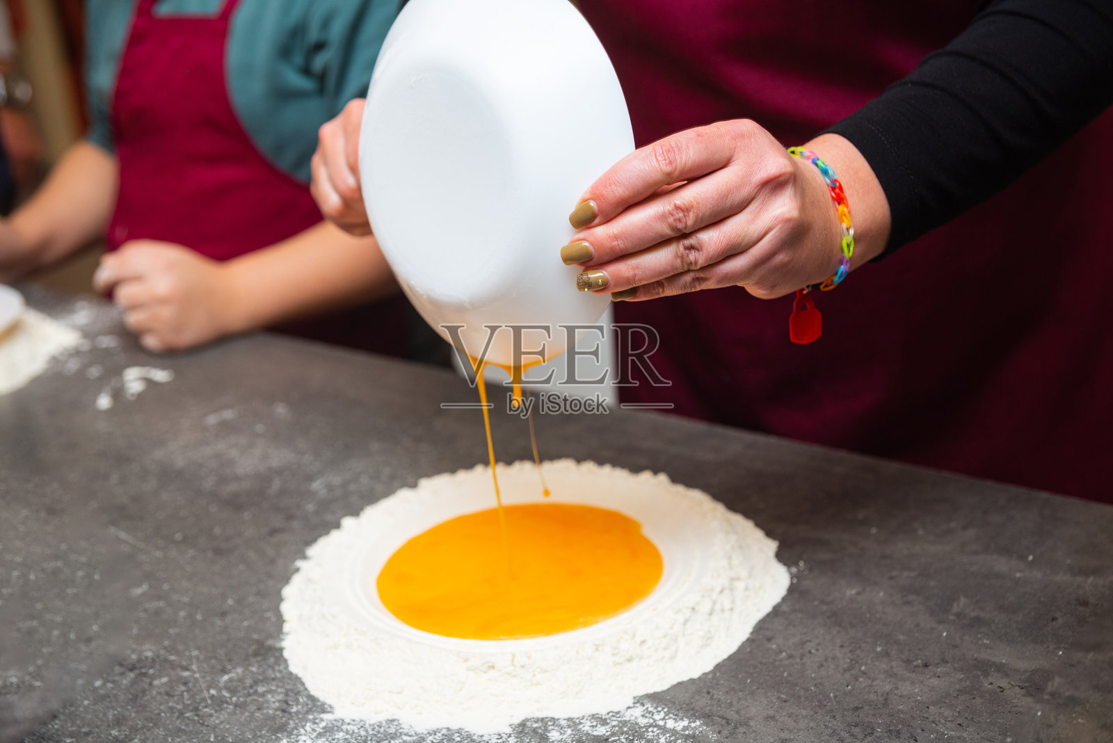 将鸡蛋倒入面粉中制作自制意大利面。照片摄影图片