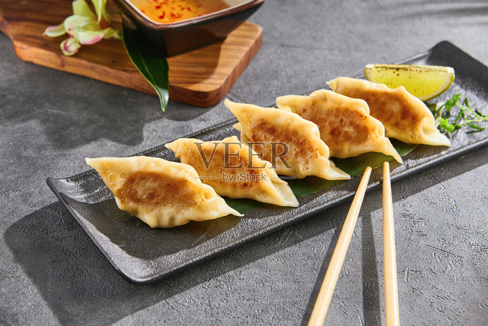 明亮灯光下的海鲜饺子，放在石板盘上，配有柠檬装饰的俯视构图照片摄影图片