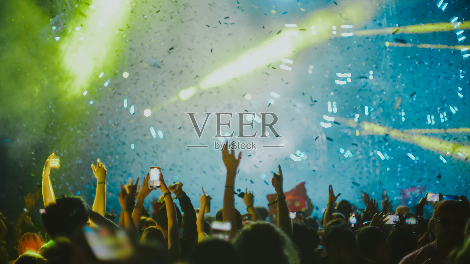 一大群人从背后观看音乐节表演，前景中的人们显得轻松愉快。照片摄影图片