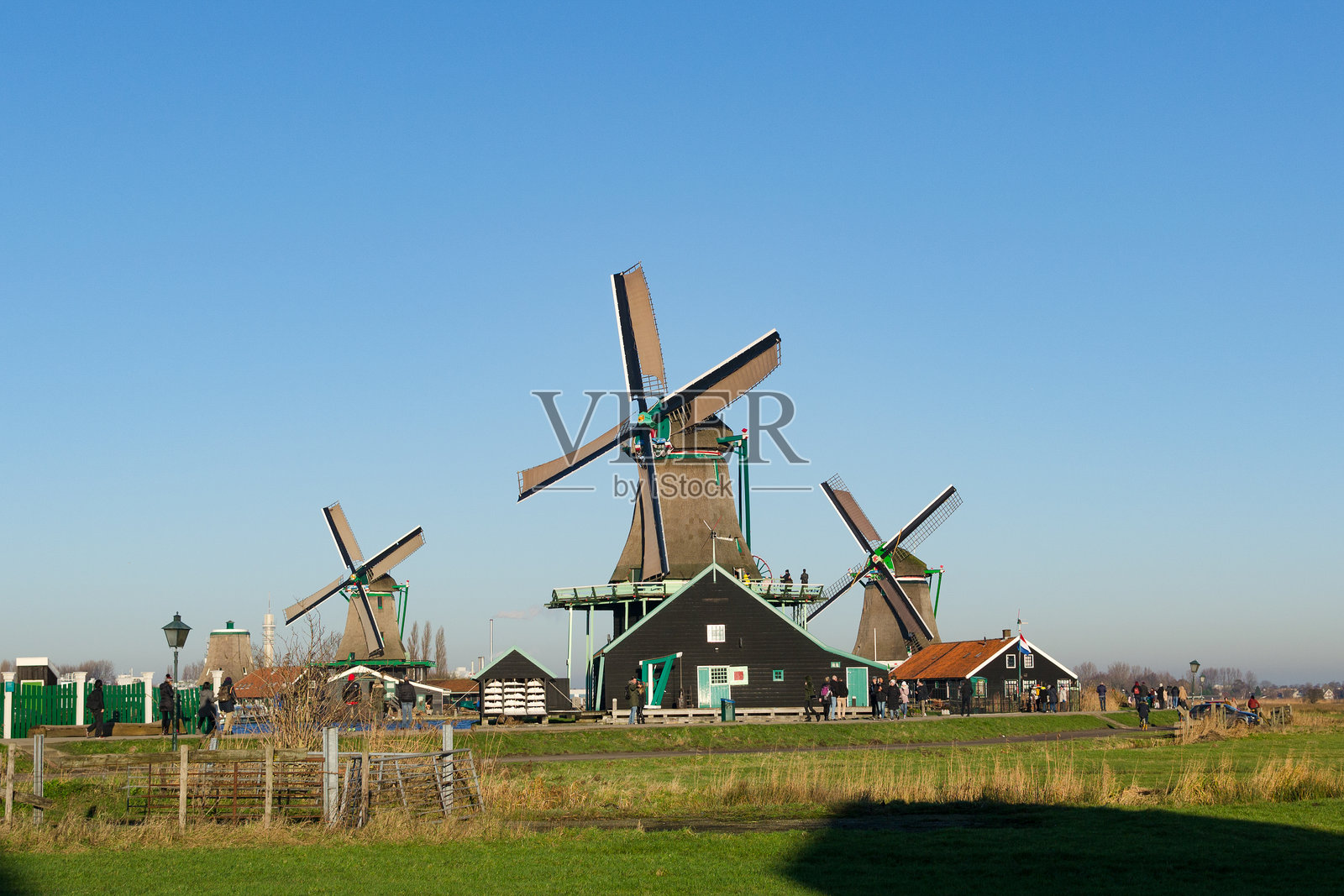 经典的风车和传统的荷兰房屋。在晴朗的日子里，受欢迎的旅游目的地，有游客前来参观。仅供编辑使用。照片摄影图片