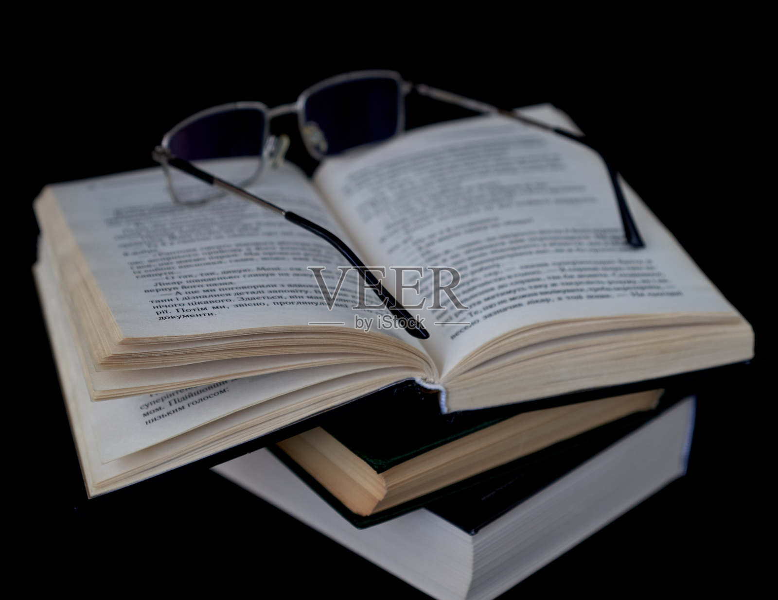 一本戴着眼镜的书躺在黑色背景上照片摄影图片