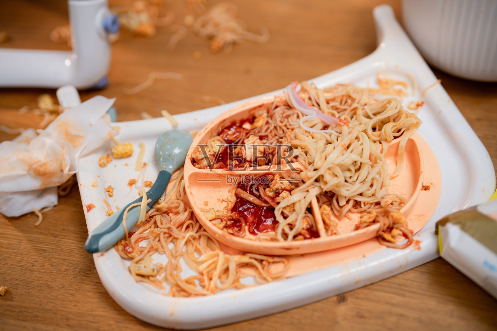 餐后儿童用餐环境中，凌乱的桌子上洒落着面条和酱汁照片摄影图片