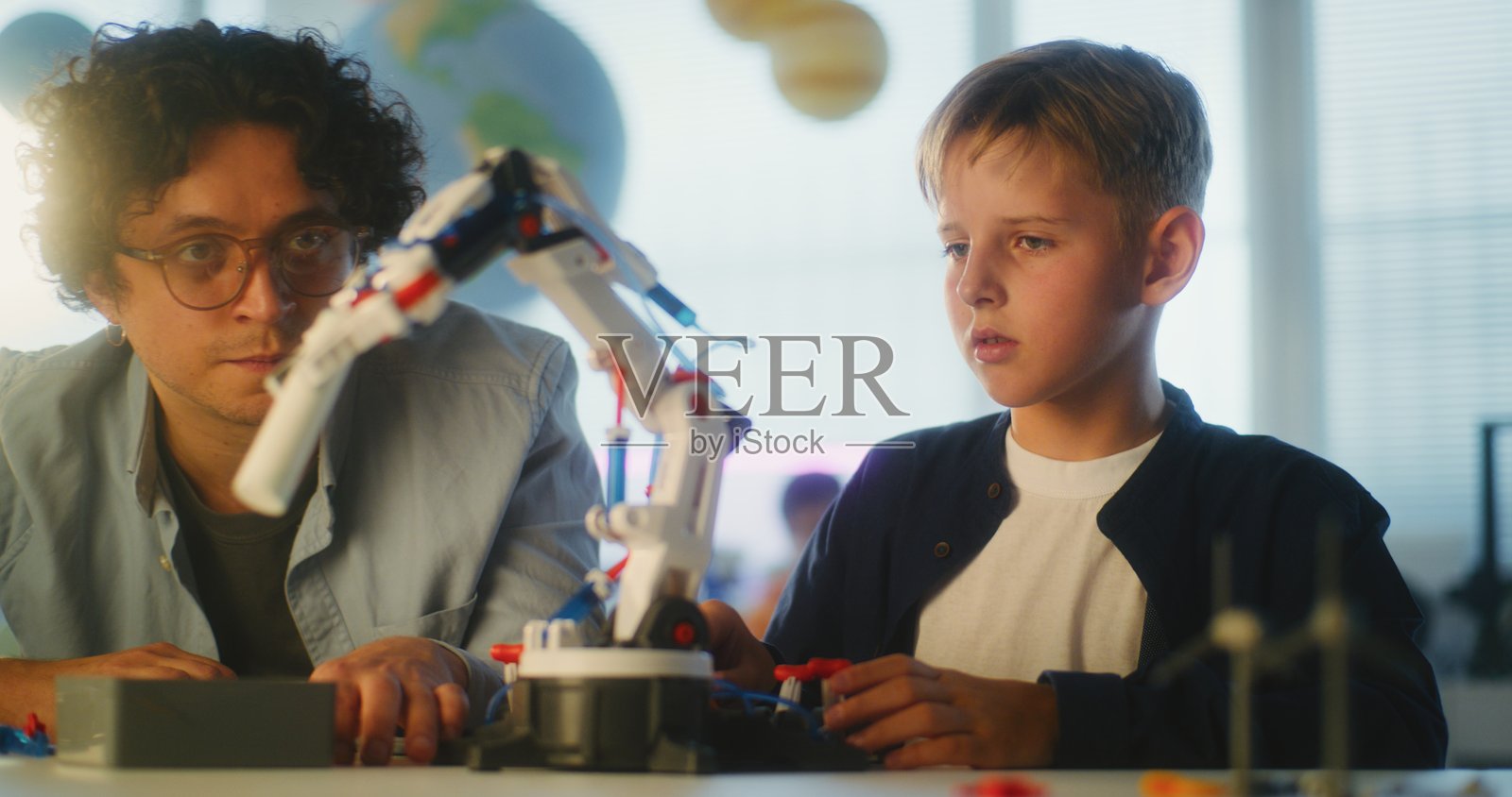 才华横溢的男孩在现代教室里与老师一起学习机器人手臂模型照片摄影图片