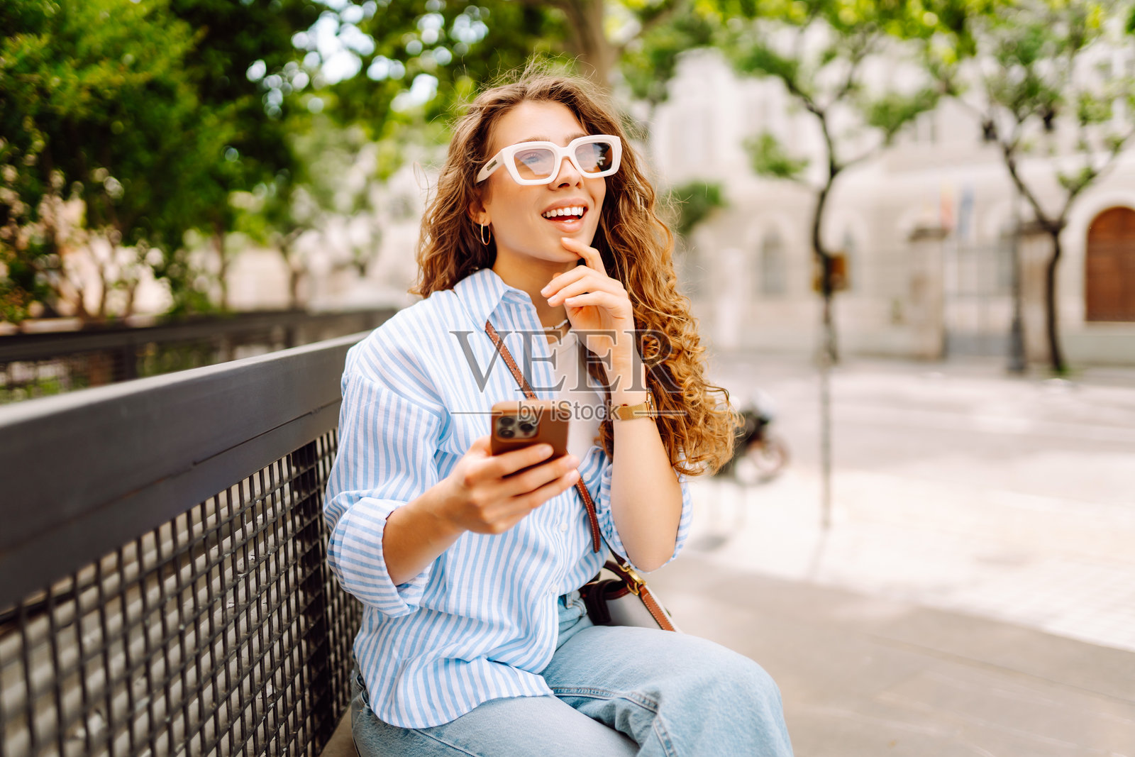 年轻女性手持手机，享受在城市中散步的时光。照片摄影图片