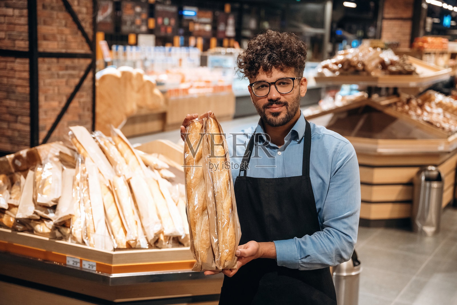 美味的面包店。男工作人员在杂货店里。照片摄影图片