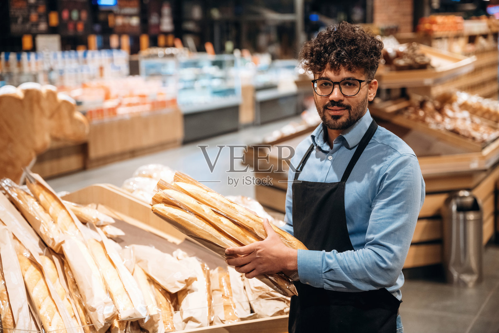 新鲜面包店。男性工作人员在杂货店内。照片摄影图片