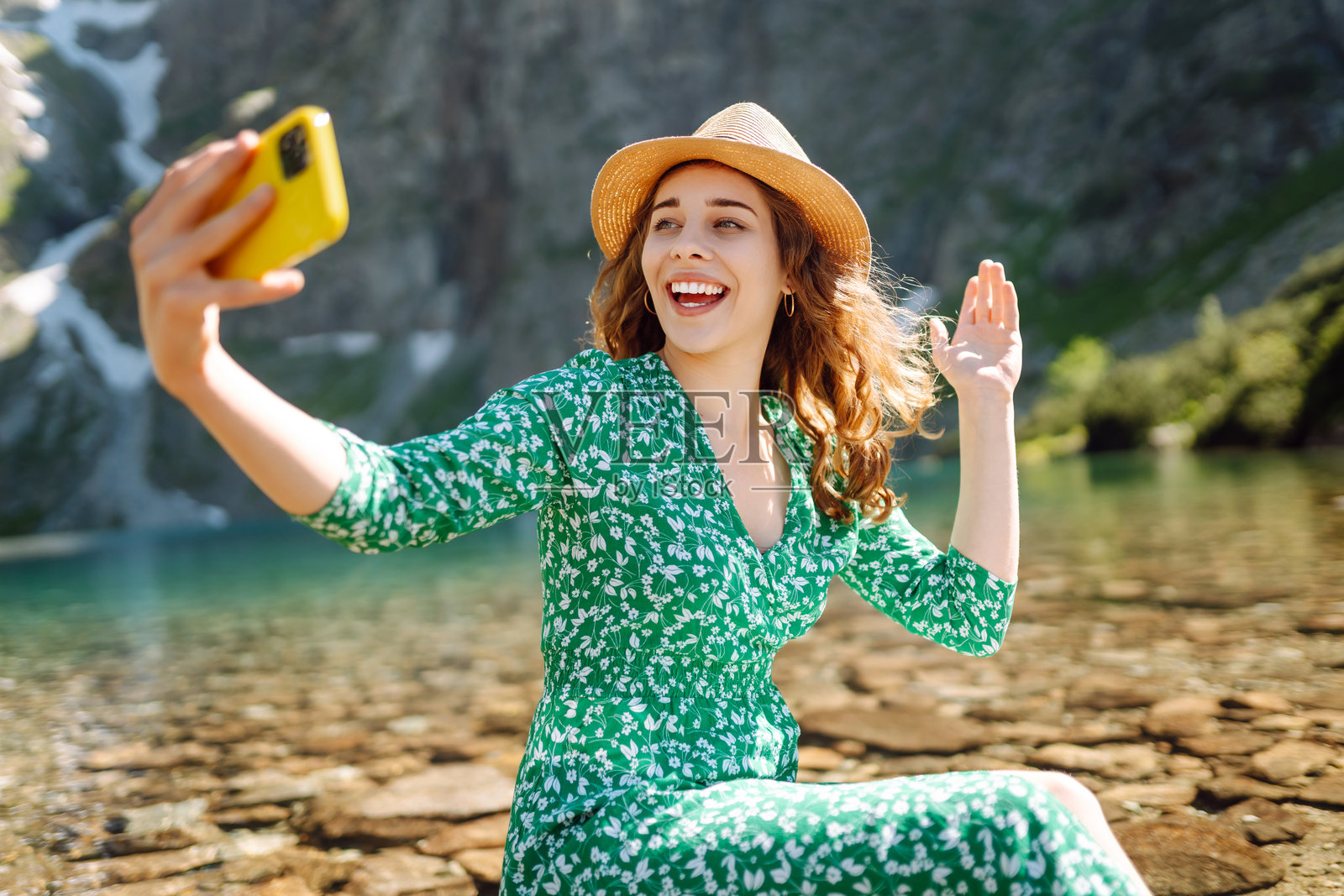 一位开心的女性在山湖的背景下用手机自拍。照片摄影图片