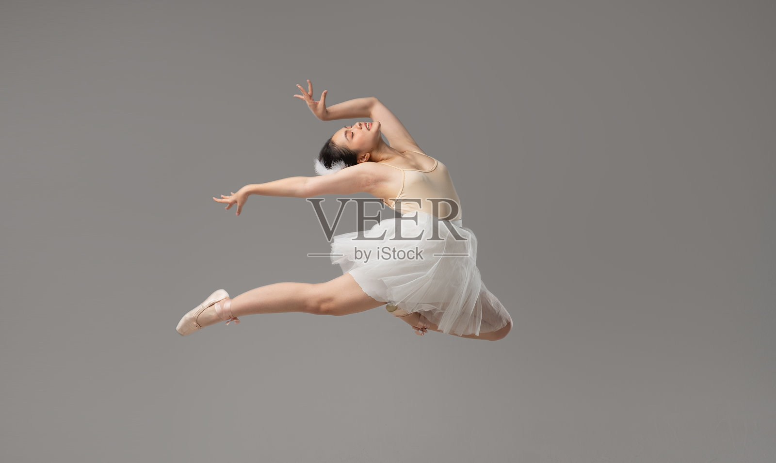 优雅的芭蕾舞者在中空中精准地跳跃，背景中呈现出优雅的动态。照片摄影图片