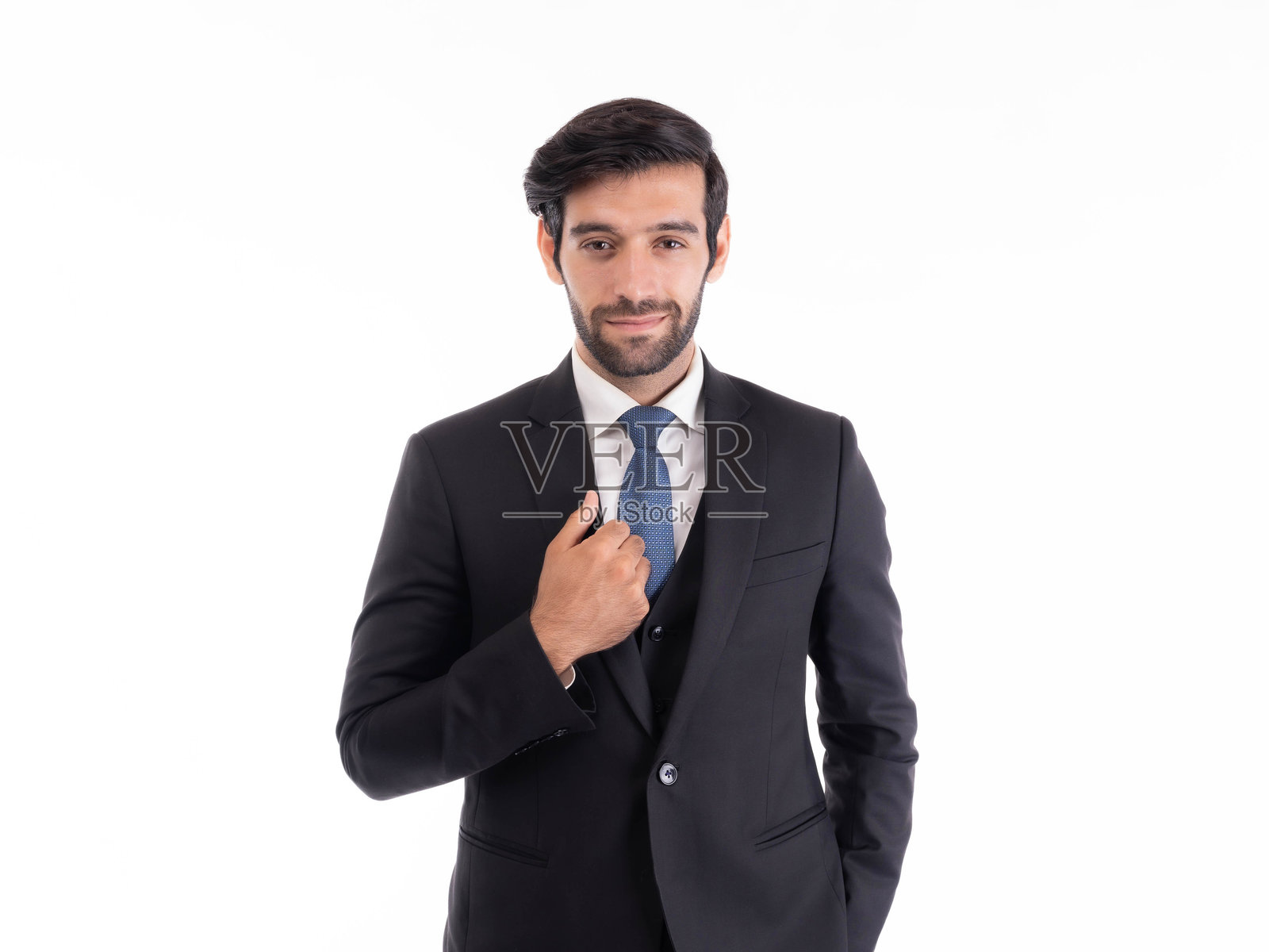 自信的年轻商人在正式的黑色西装和蓝色领带中调整着自己的服装，专业地站立在白色背景上，企业高管肖像概念照片摄影图片