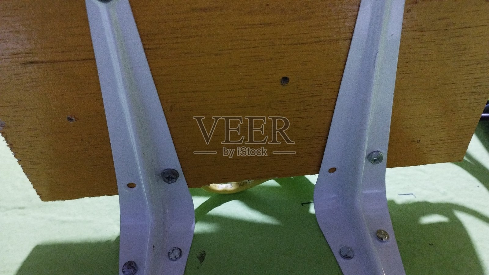 两个角钢或L形支架用作支撑黄色板，以制作悬挂在其上方的架子。照片摄影图片