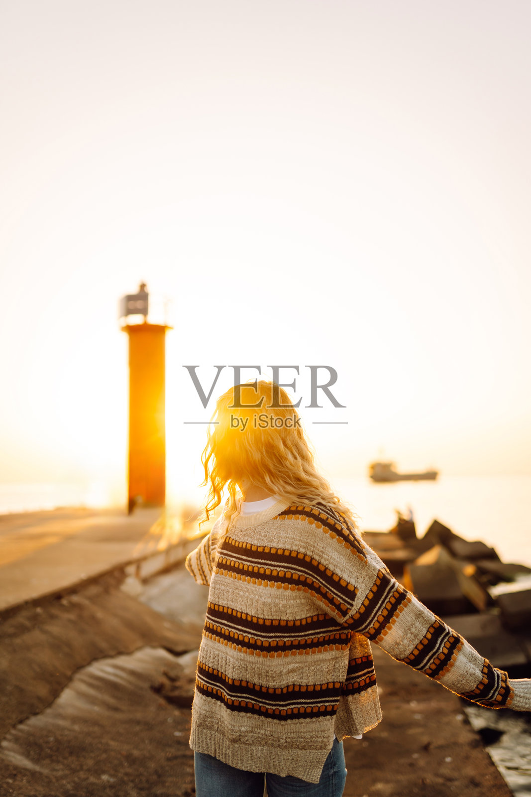 放松的女人站在码头上欣赏日落。照片摄影图片