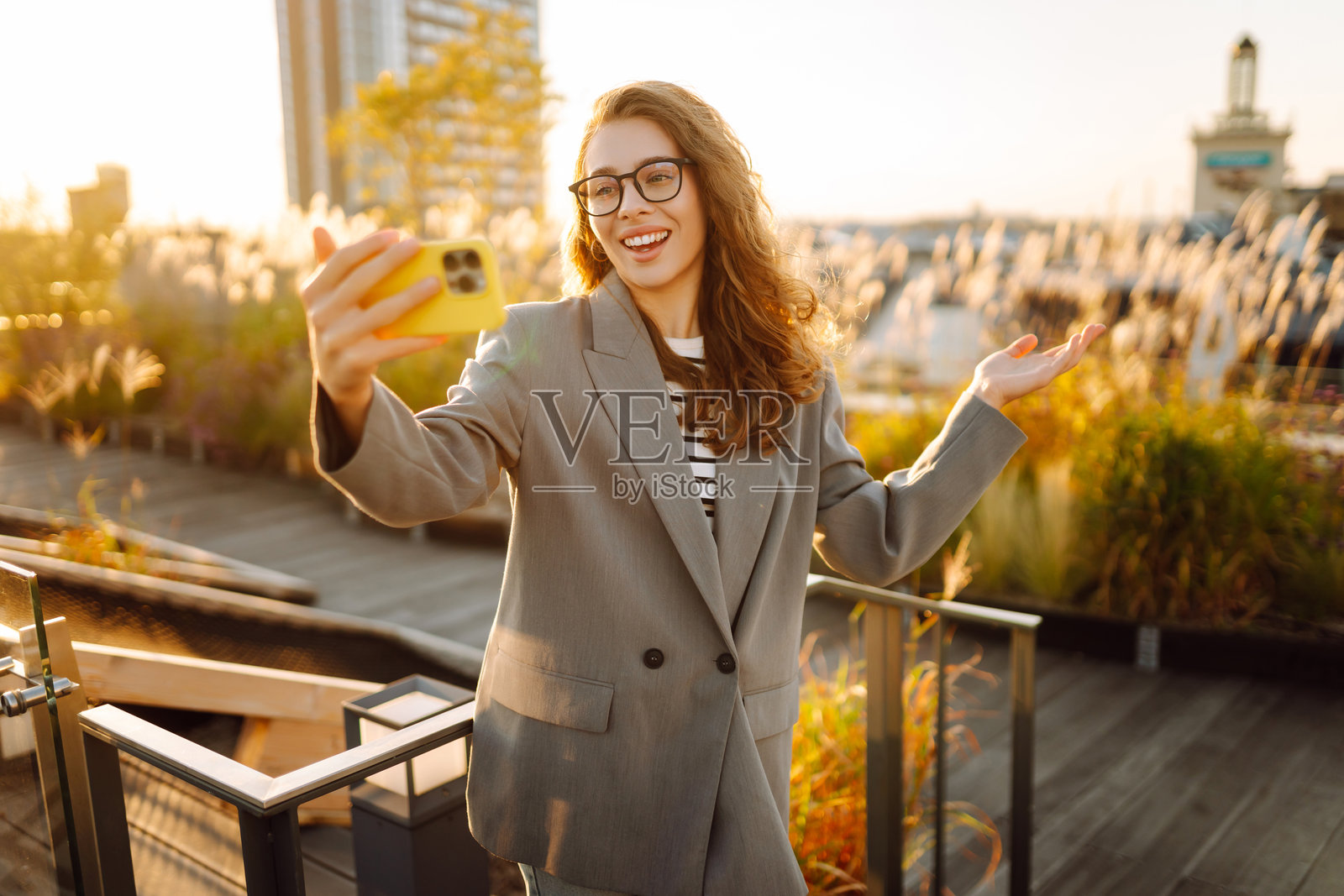 一位美丽的女性在享受日落时用手机自拍。照片摄影图片