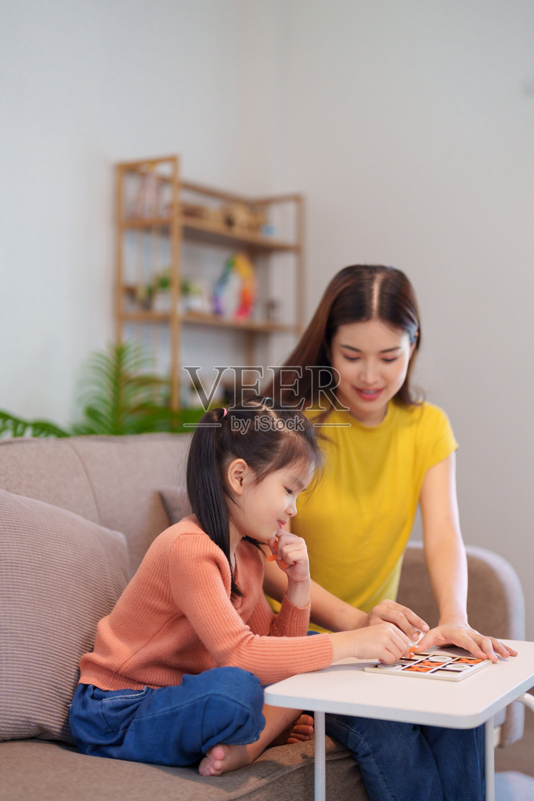 母女俩在桌子上愉快地玩井字游戏，分享欢笑和亲密的时刻。照片摄影图片