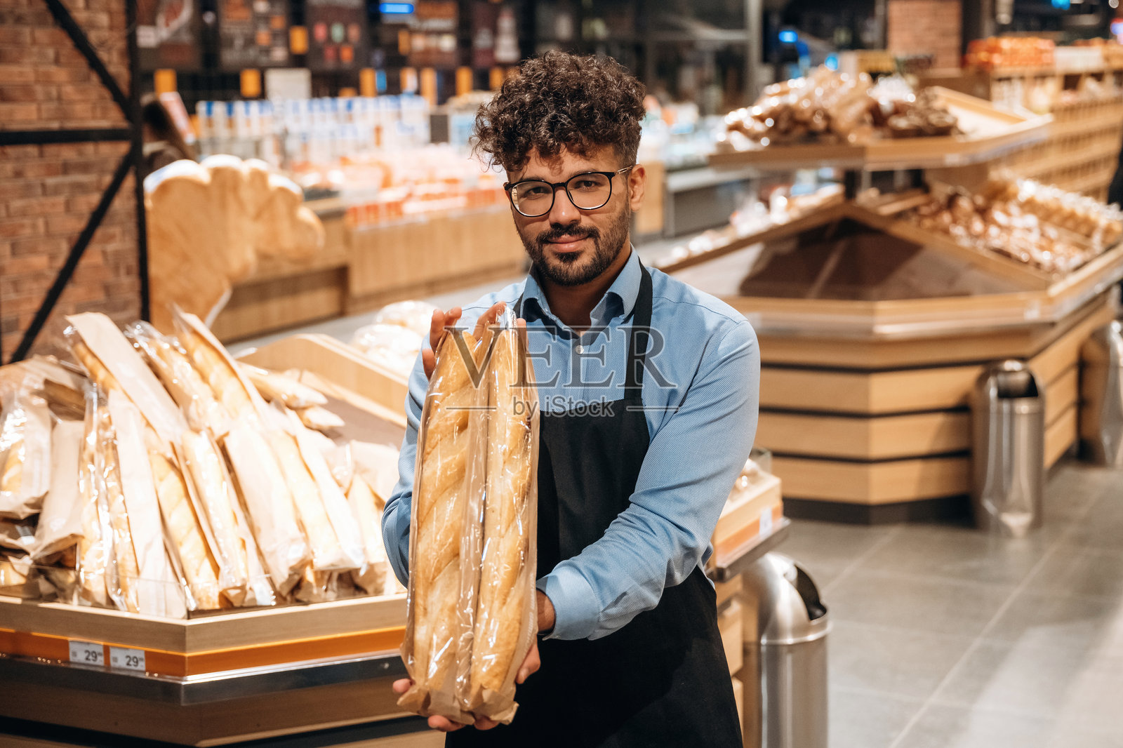 新鲜面包店。男员工在杂货店里。照片摄影图片