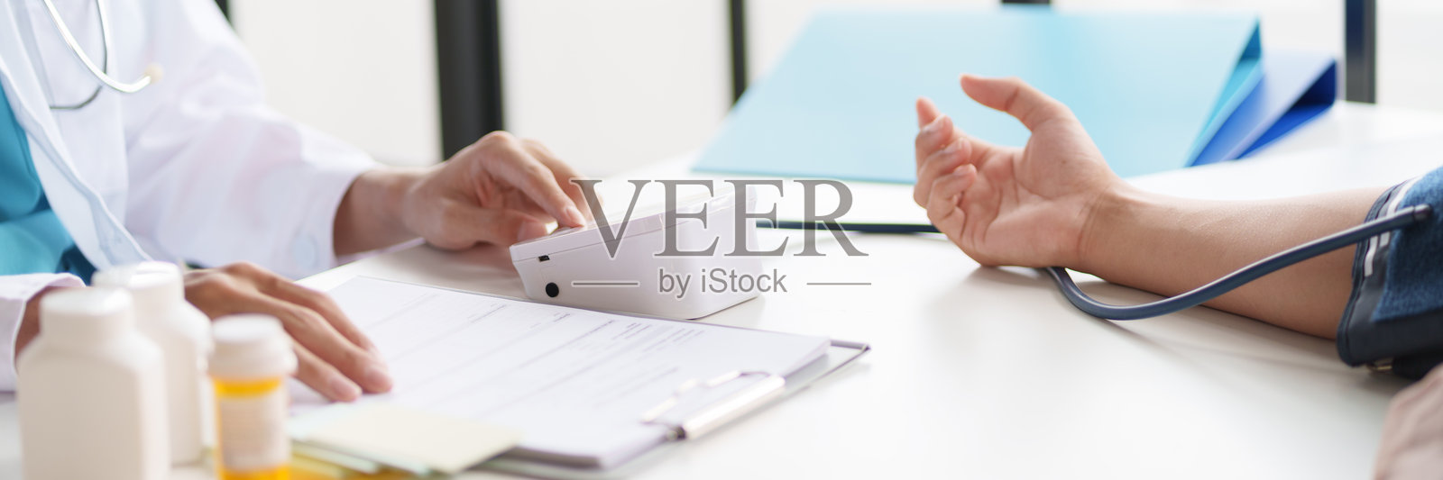 医生正在为患者测量血压。患者的手臂上装有血压袖带，医生正在使用血压监测仪。照片摄影图片