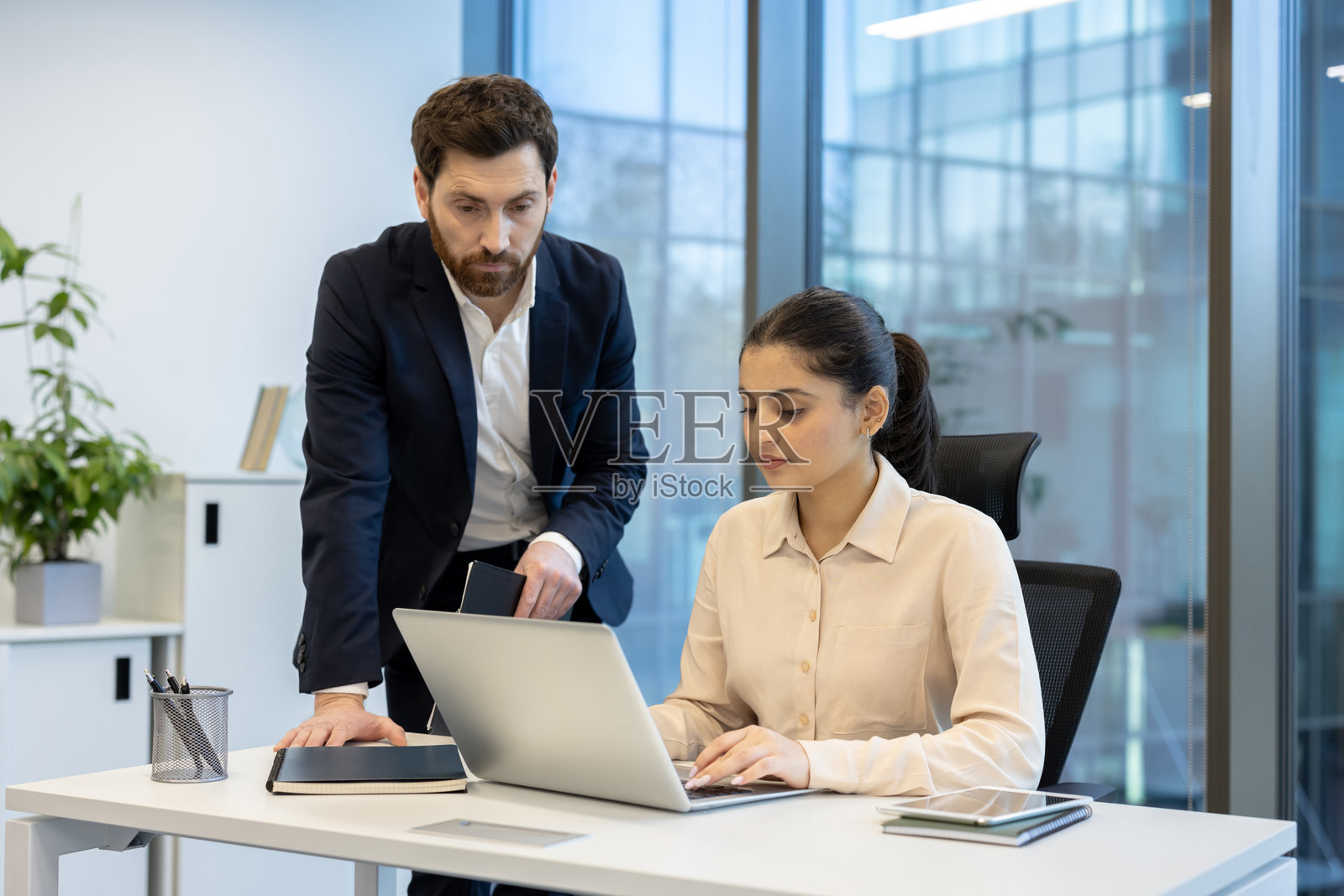 一位男商人和一位女商人在现代办公室里一起使用笔记本电脑。照片摄影图片