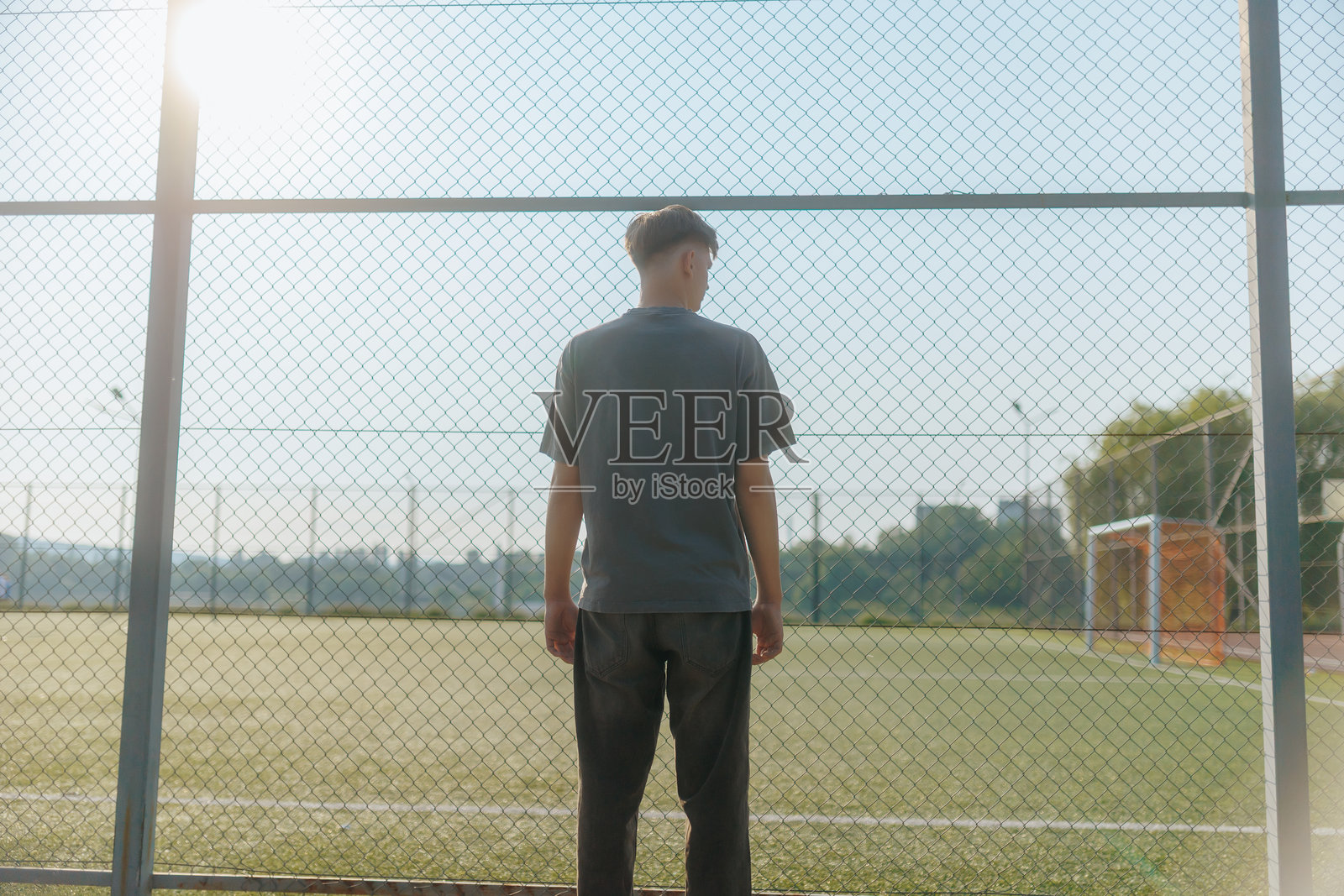 青少年面对空荡荡的足球门，沉浸在思绪和回忆中照片摄影图片