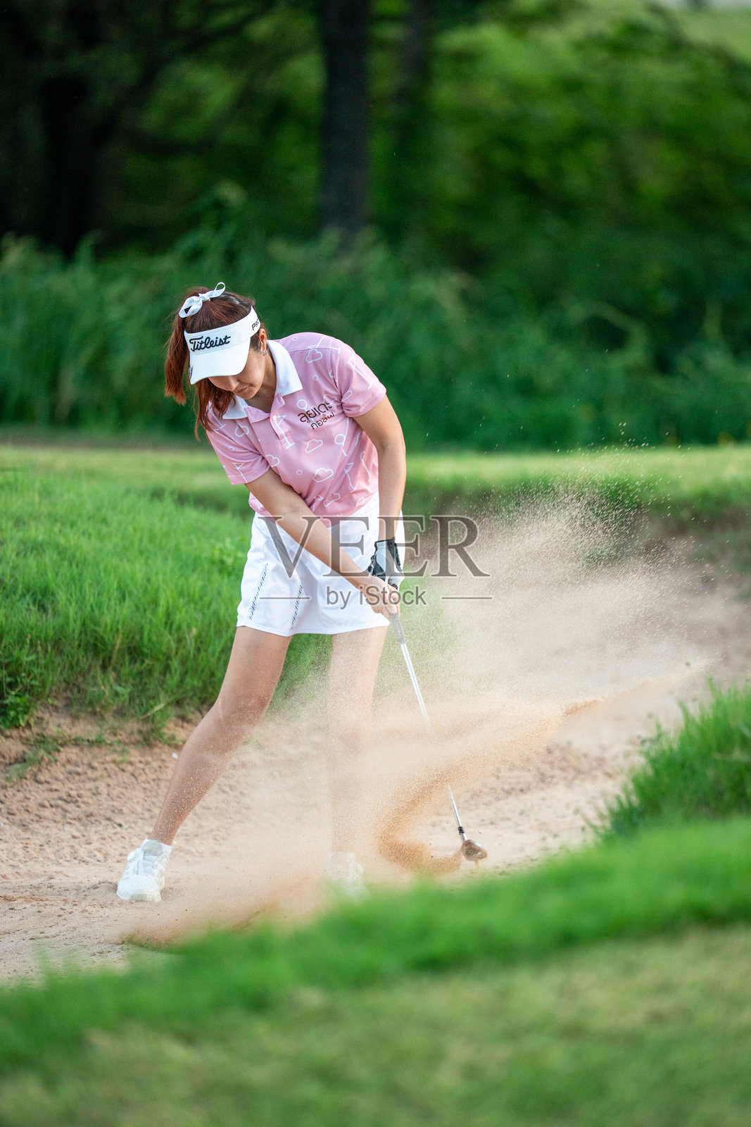 一位女性正在打高尔夫球，挥动着她的球杆。照片摄影图片