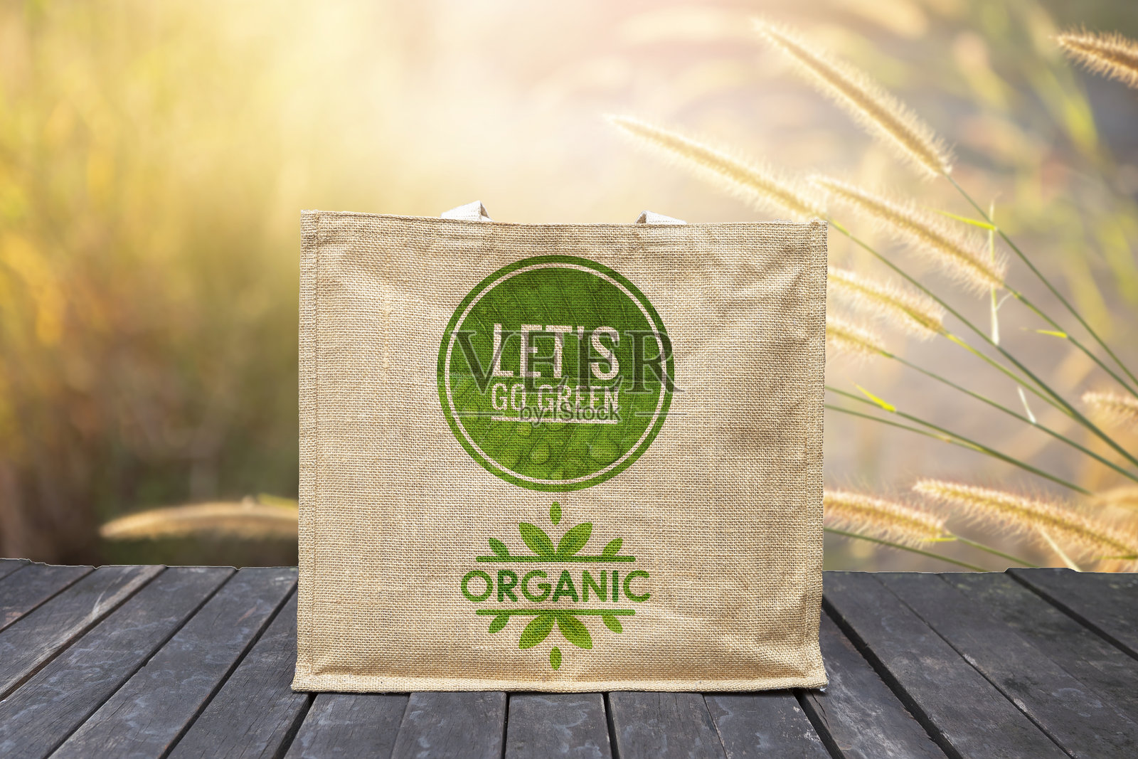 木地板上的麻袋，带有绿色标志，背景模糊的自然景色照片摄影图片