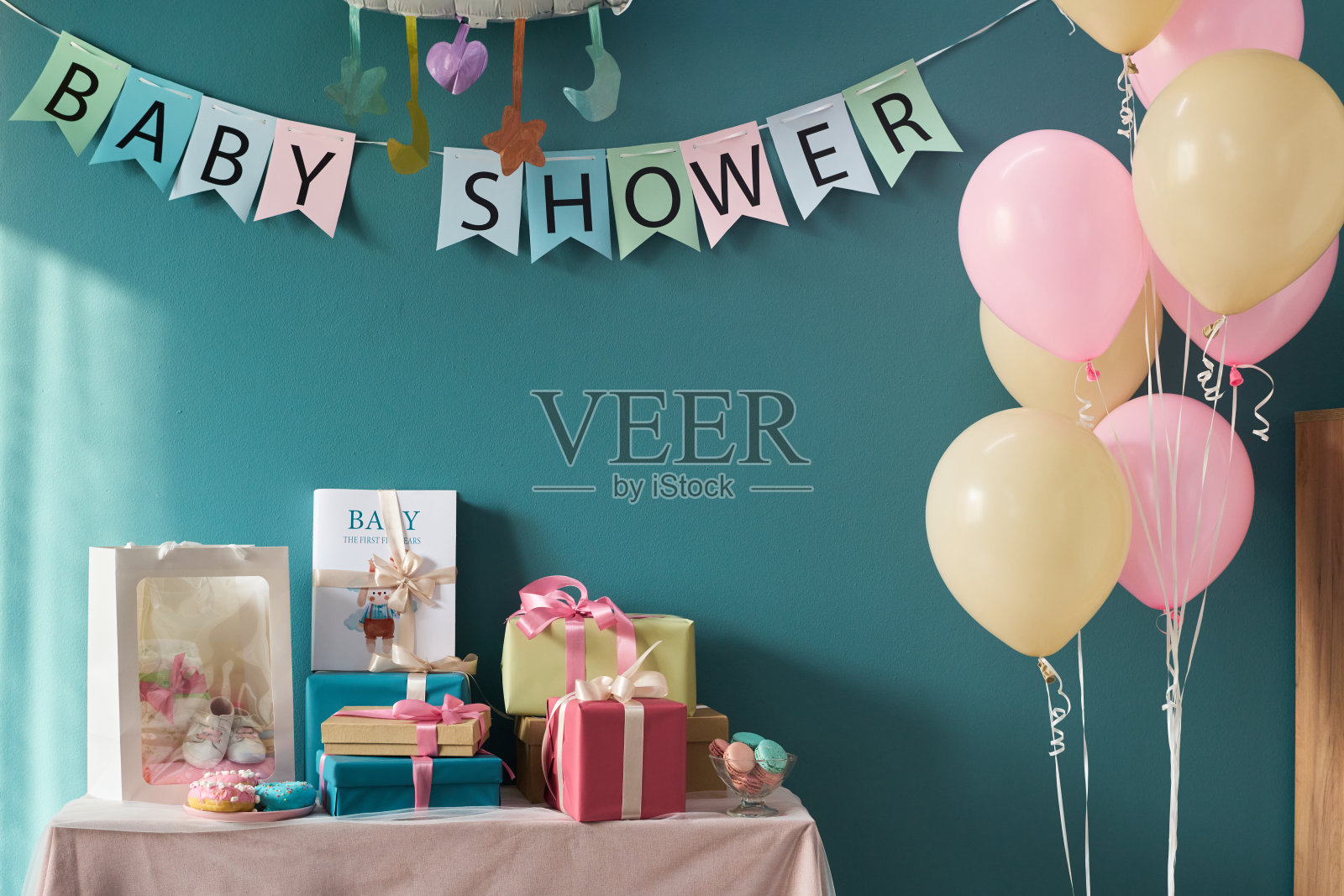 装饰好的性别揭晓派对桌子，上面有包好的礼物、气球和婴儿洗礼横幅照片摄影图片