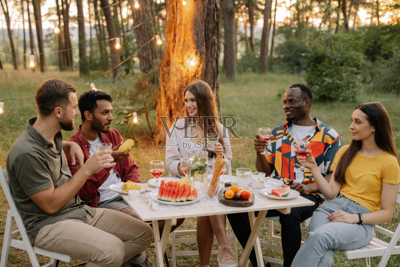 不同种族的朋友们在树林中愉快地享受野餐照片摄影图片
