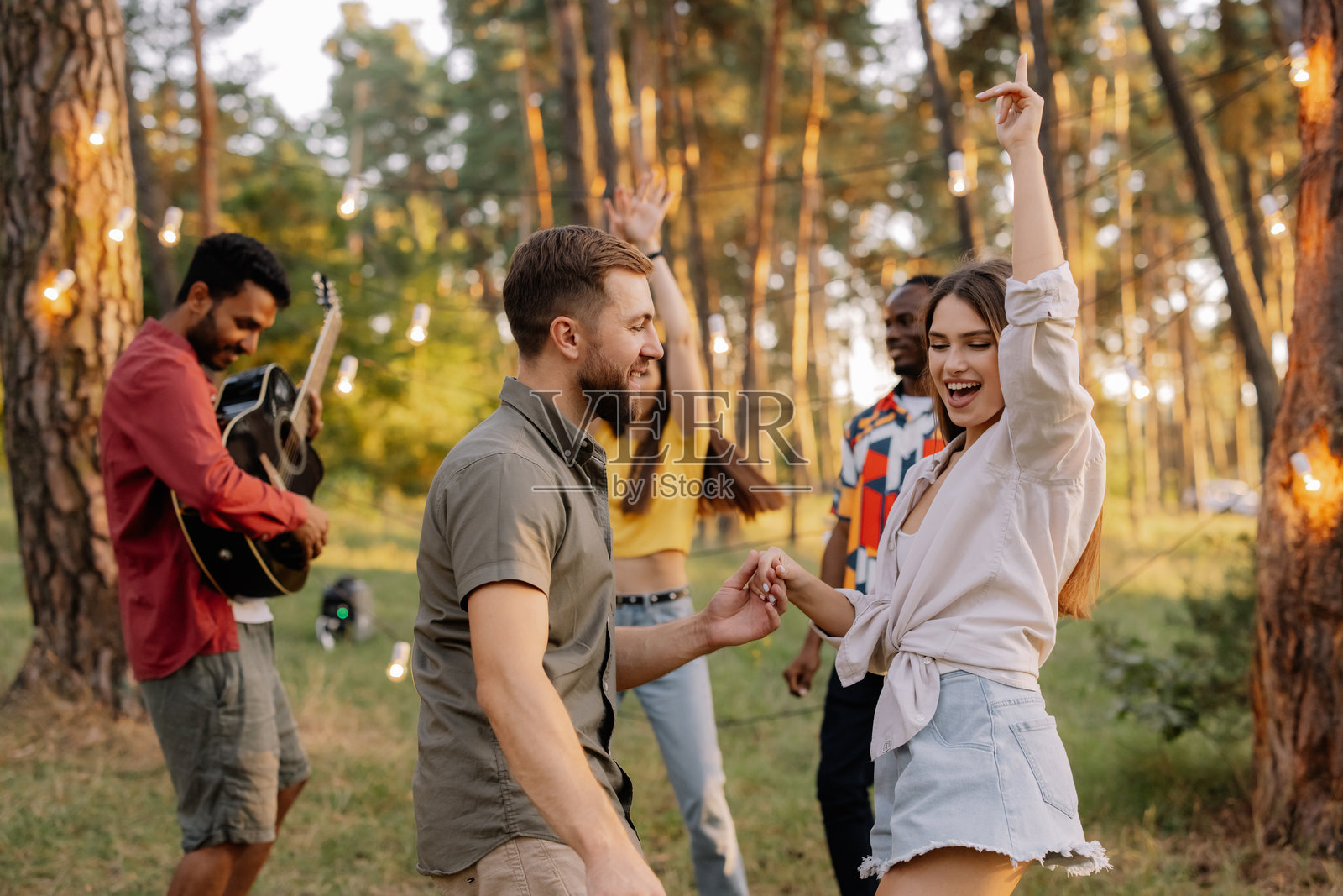 不同种族的朋友在森林派对上跳舞和弹吉他照片摄影图片