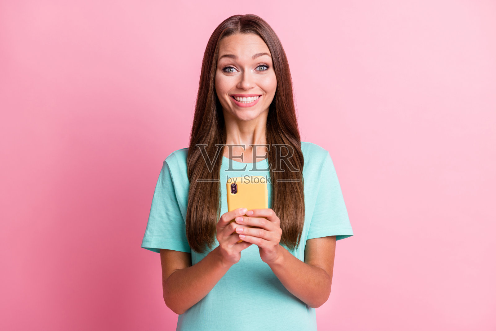 年轻快乐、微笑、迷人的女性博主在粉色背景下使用智能手机的照片照片摄影图片