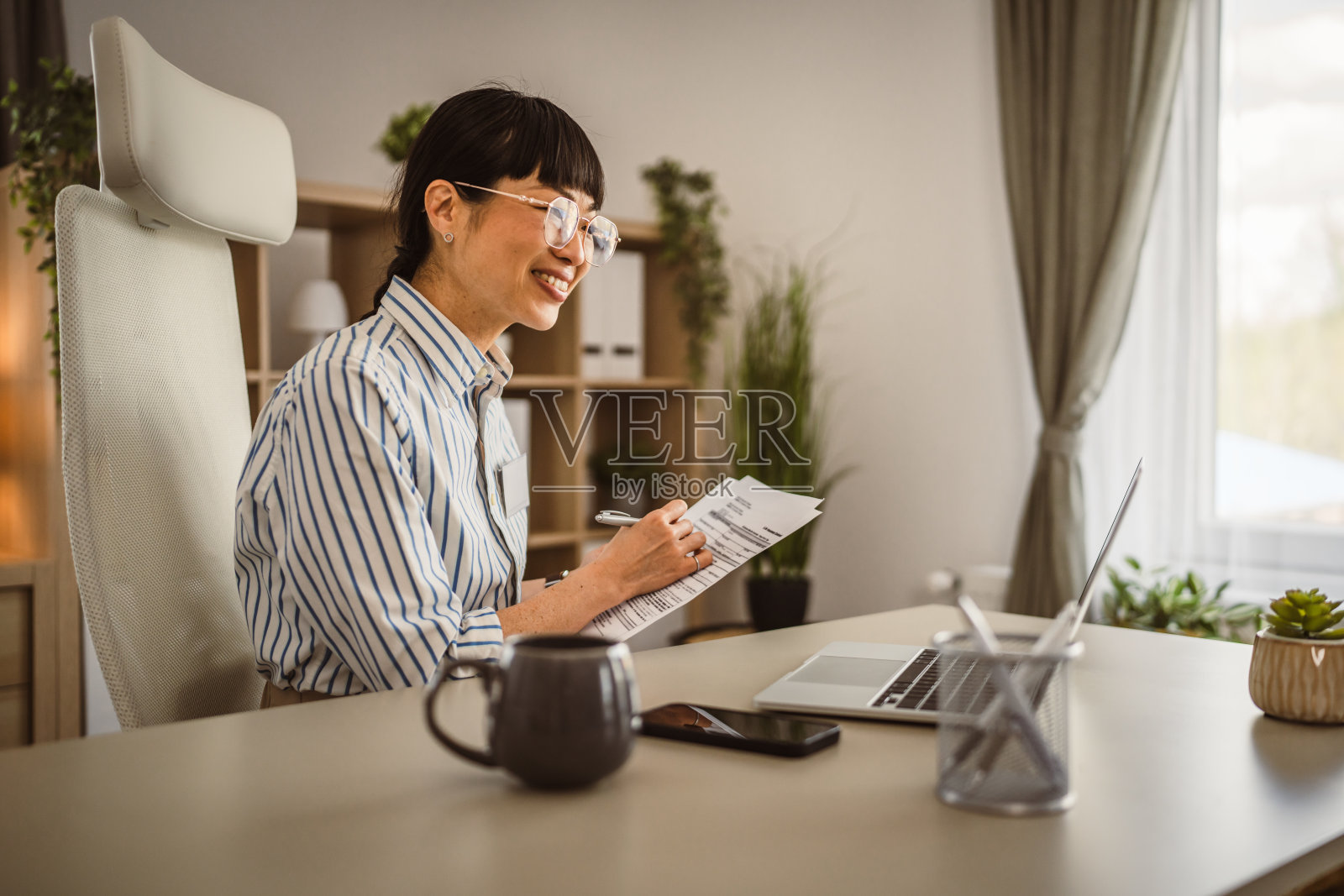 成熟的日本女性手持文件，通过视频通话进行咨询照片摄影图片