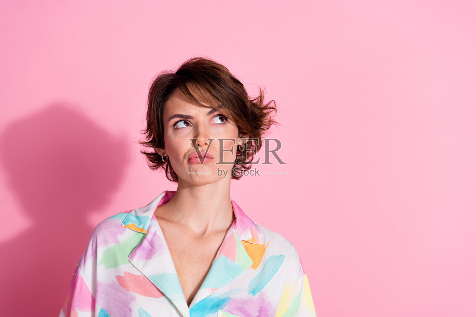 漂亮年轻女孩的肖像，目光空灵，穿着衬衫，背景为粉色。照片摄影图片