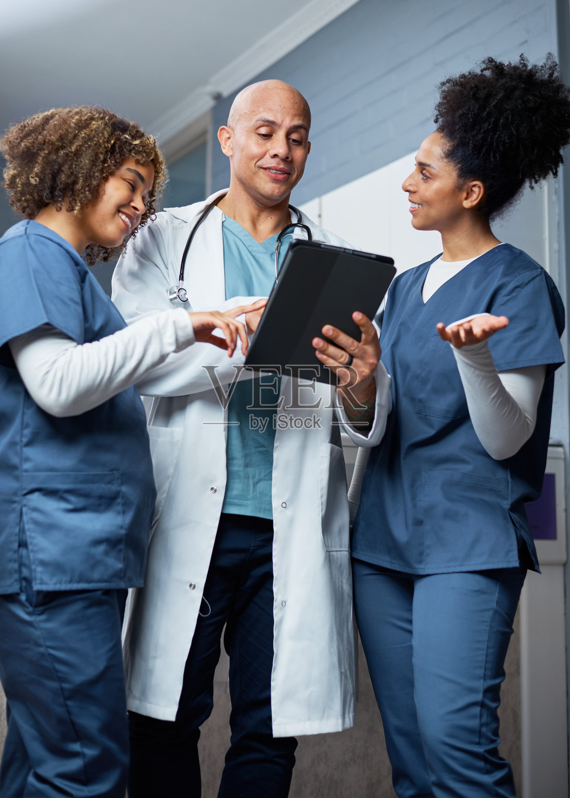 医疗团队在明亮的诊所环境中使用数字平板讨论患者数据照片摄影图片