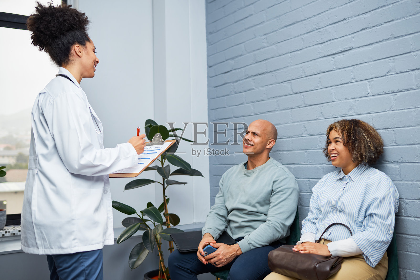 医生在诊所与微笑的夫妇进行咨询讨论照片摄影图片