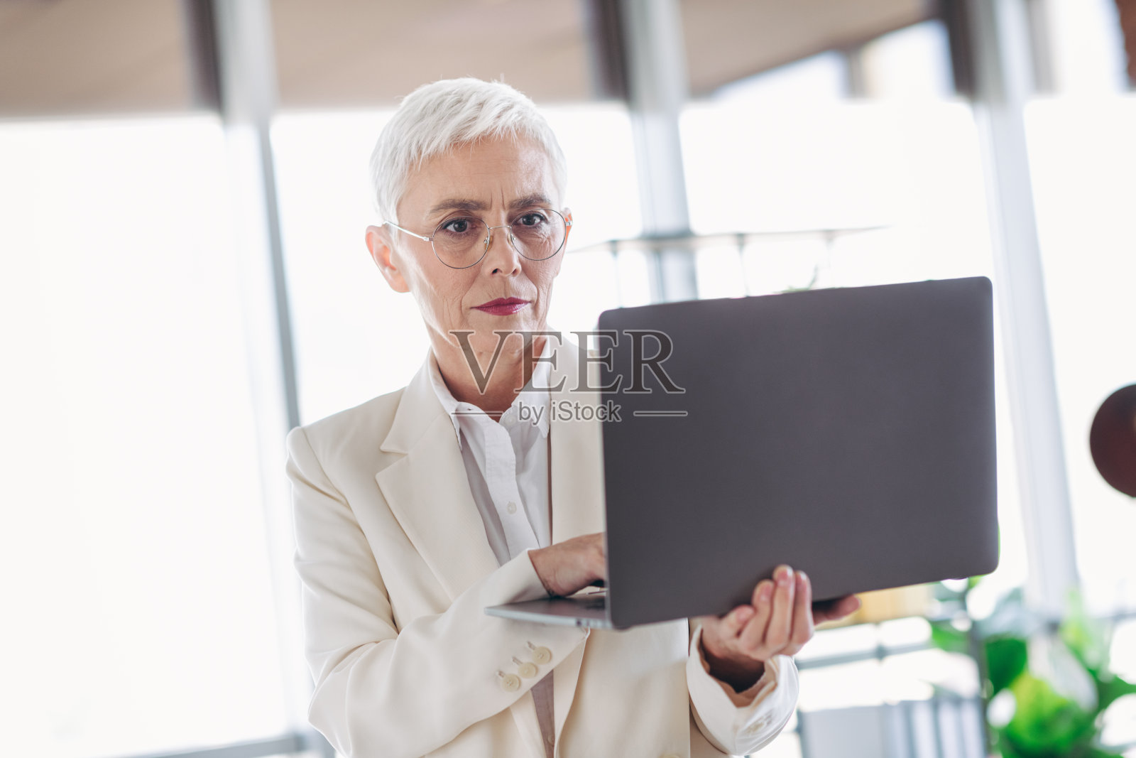 自信且专业的成熟的女商人在现代办公室环境中使用笔记本电脑工作照片摄影图片