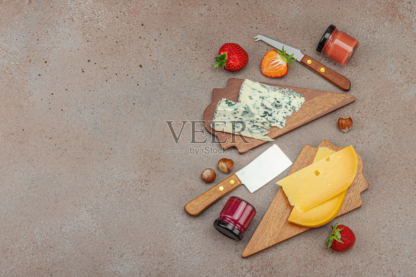 木板上的奶酪拼盘，搭配草莓、坚果和果酱，背景为石材。照片摄影图片