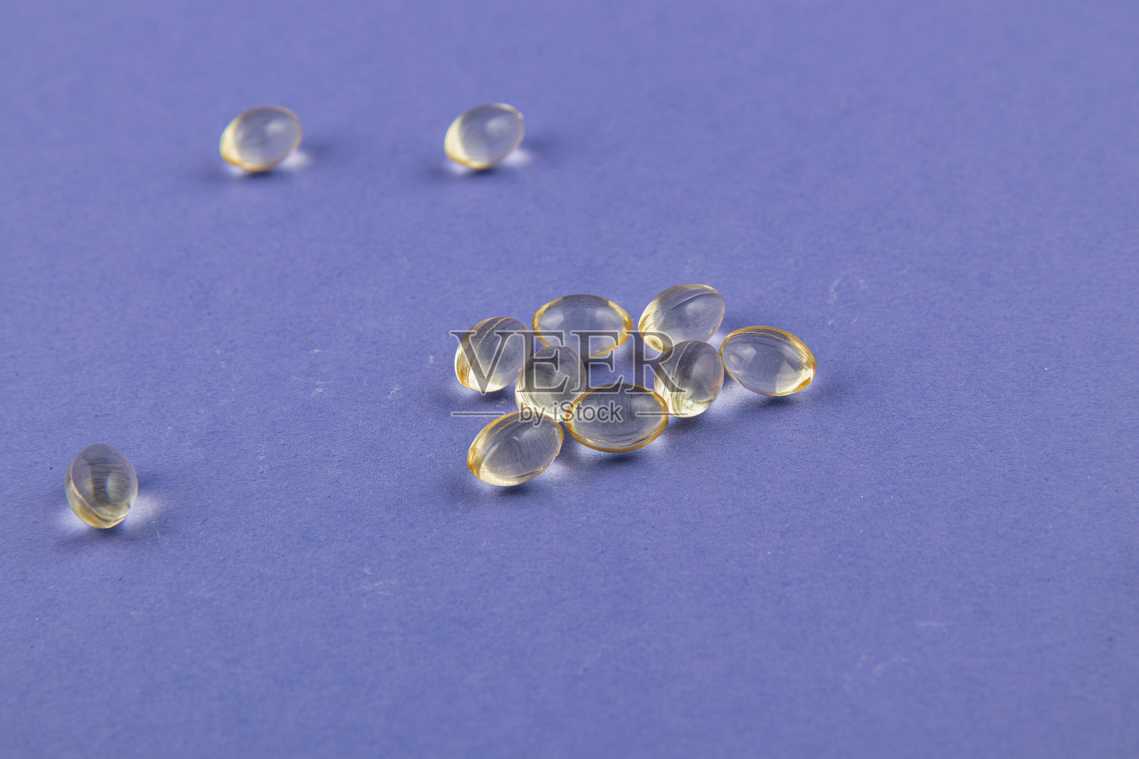 小透明胶囊散落在紫色表面上照片摄影图片