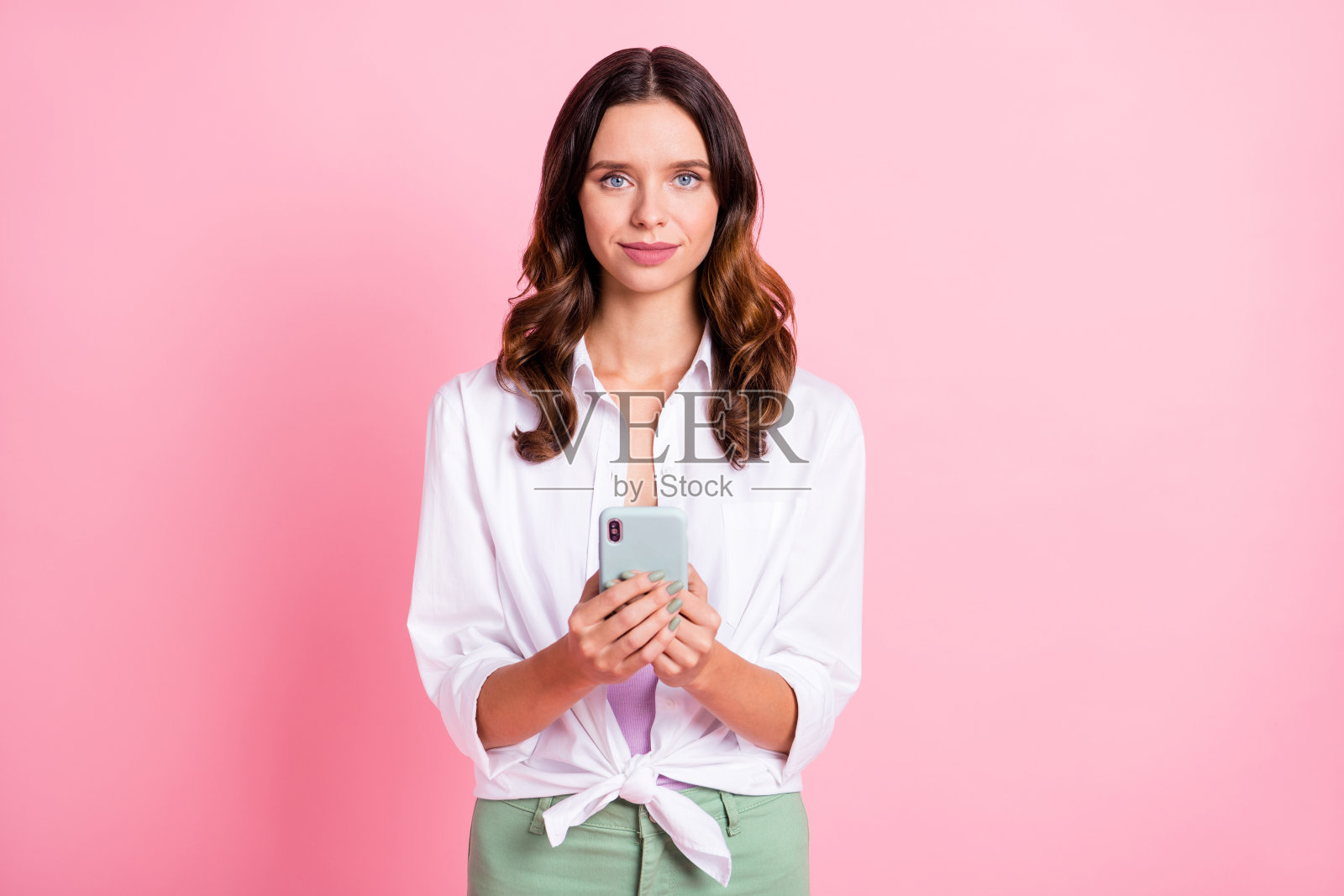 年轻漂亮女孩认真使用智能手机聊天、发短信、浏览互联网，背景为柔和的色彩。照片摄影图片