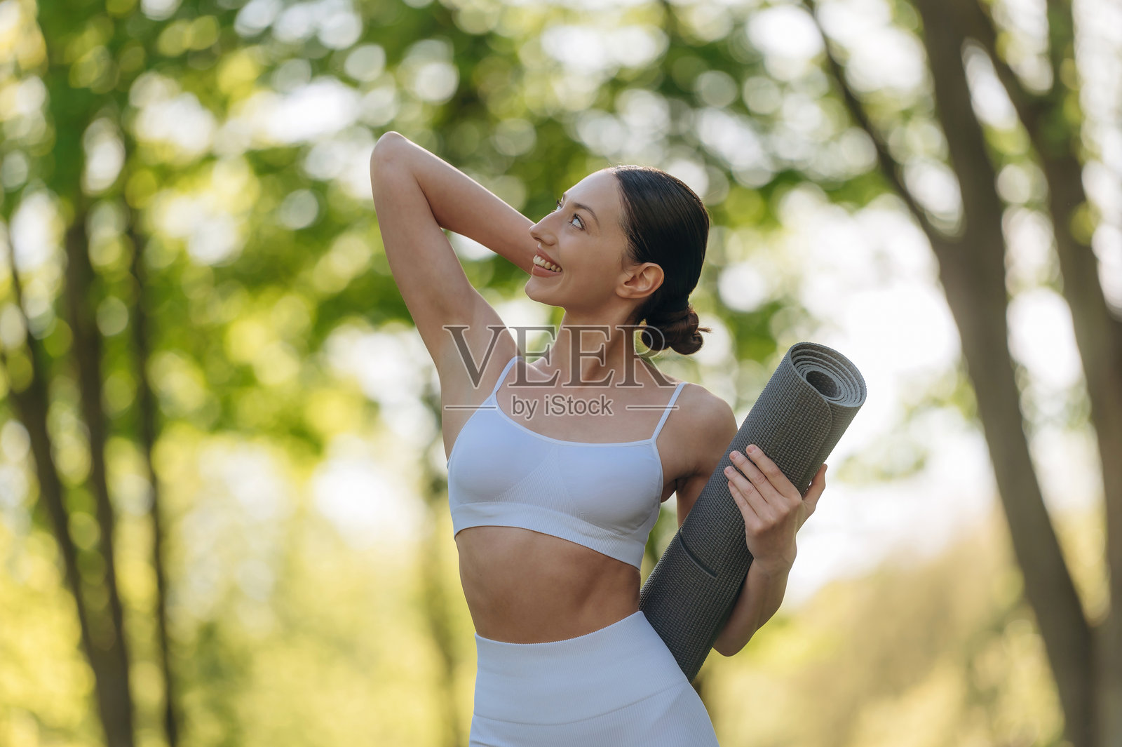 仅仅站着摆姿势。美丽的健身瑜伽女性在户外，享受着迷人的自然风光。照片摄影图片